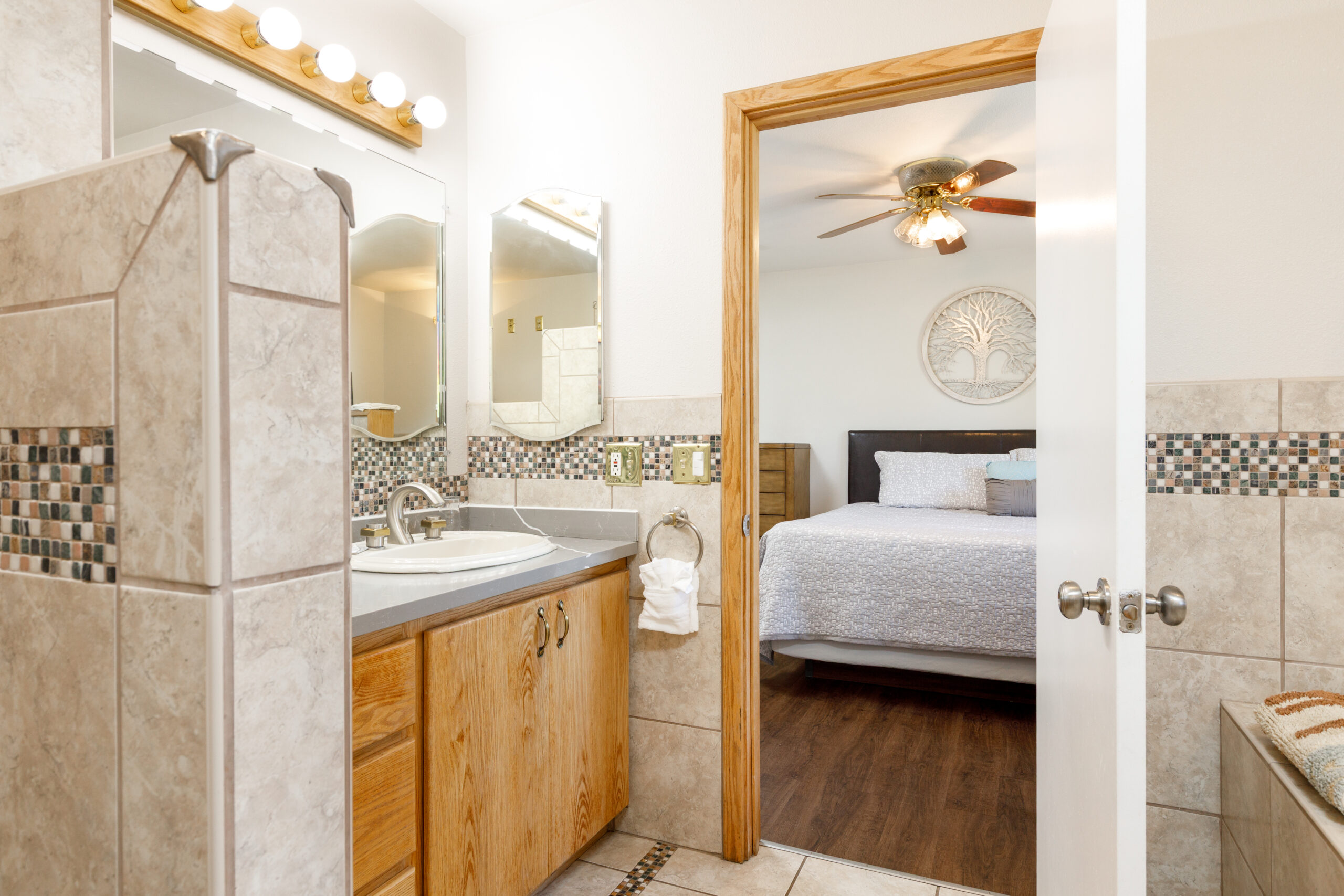 Bathroom with tiled shower and view into bedroom at Soap Lake Resort Beach House